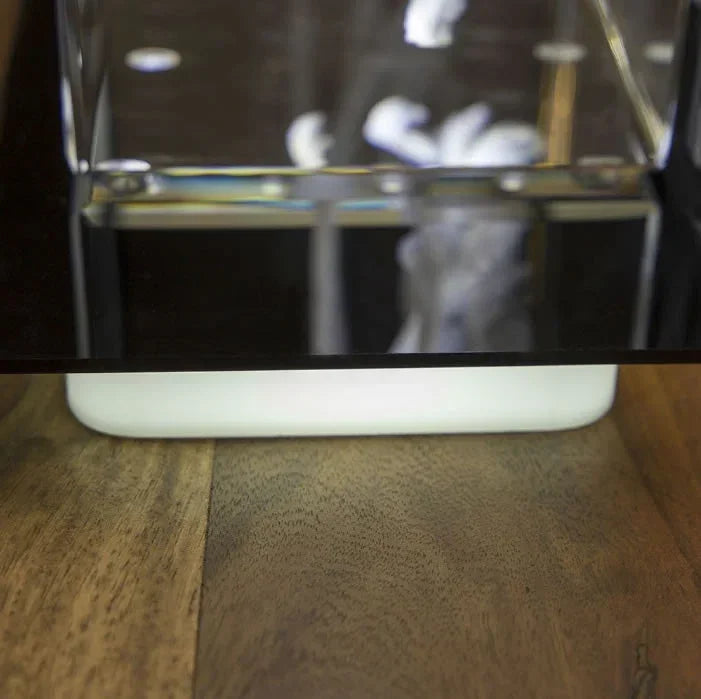 Détail d'un bloc de verre gravé avec socle lumineux posé sur une table en bois