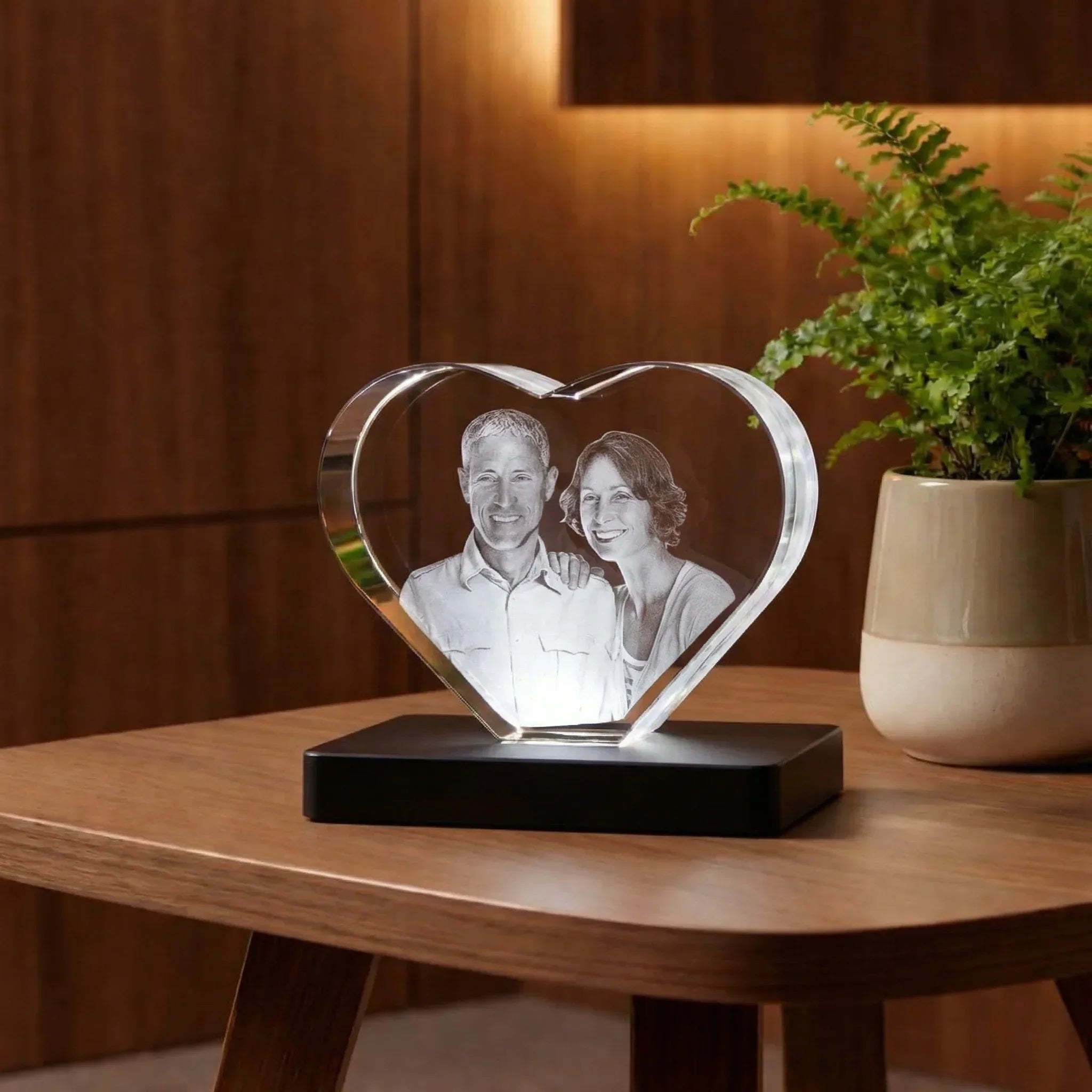 Photo gravée dans un cœur en verre 3D personnalisé, posé sur une table en bois.
