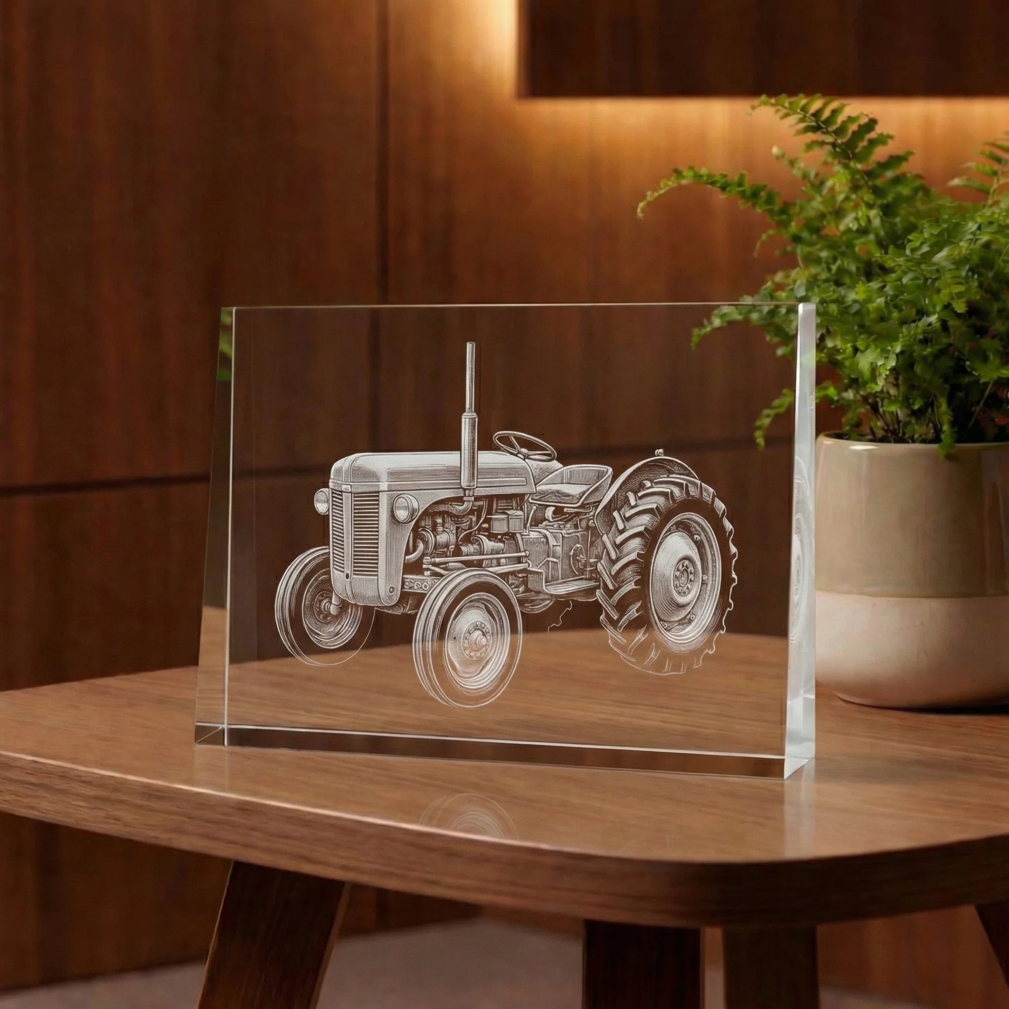 Prisme en verre avec gravure d’un tracteur, posé sur une table en bois, décoration élégante.