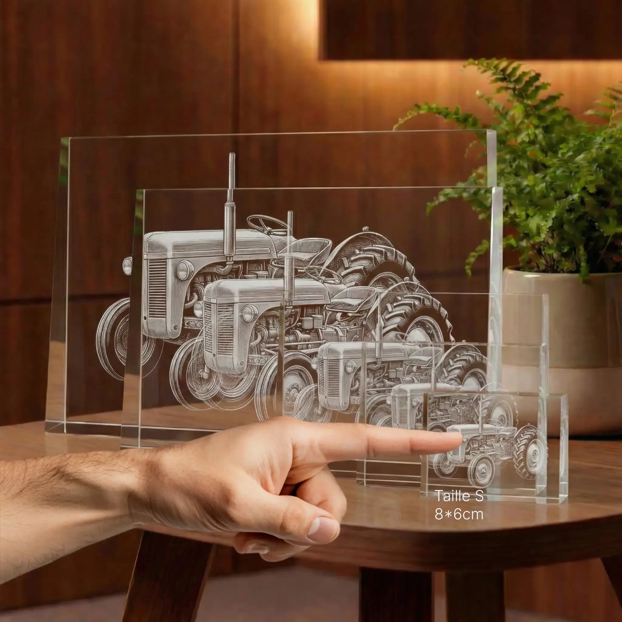 Prisme en verre gravé d’un tracteur, différentes tailles, posé sur une table en bois.