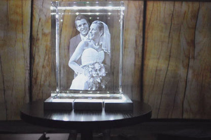 Vidéo d'un Bloc de Verre XXL Portrait - Gravure Laser 3D d'un couple de mariés avec un bouquet de fleurs sur un socle lumineux.